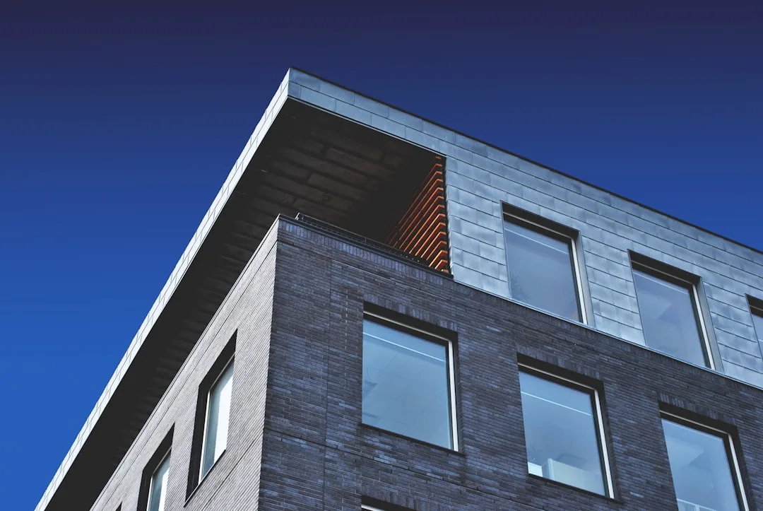 Modern building with a brick and metal facade under a clear blue sky, perfect for fast transactions or cash purchase opportunities.